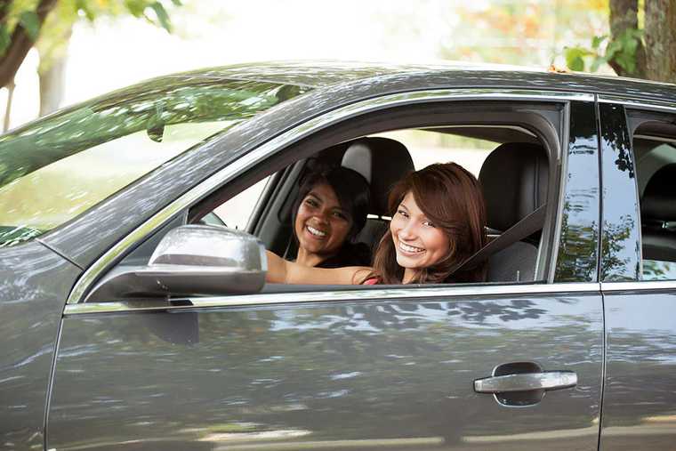 Two girls sitting in a car smiling