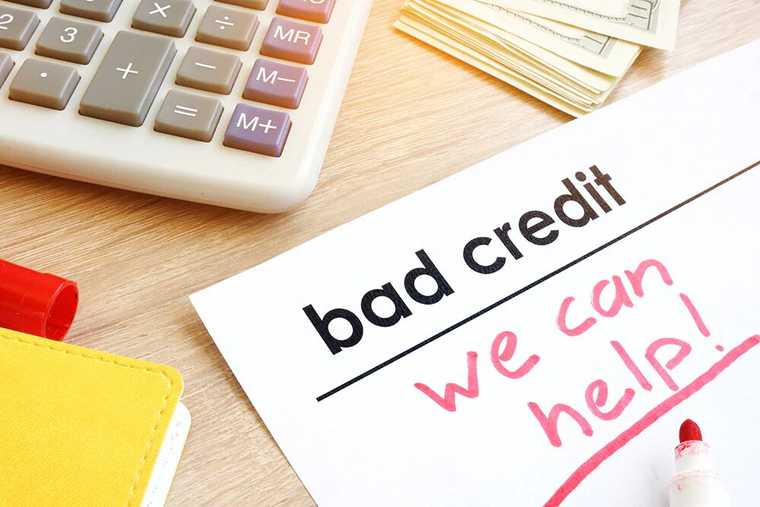 A calculator and a piece of paper with text 'bad credit we can help' on it