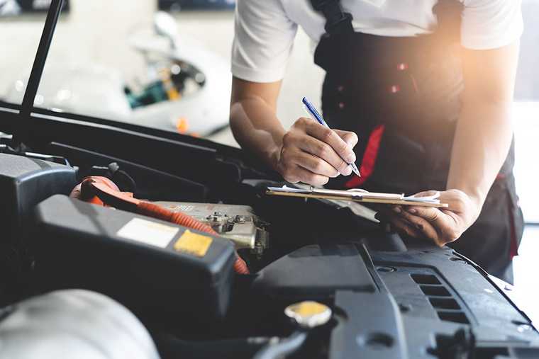 A car mechanic checking a vehicle and writing report