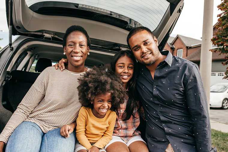 A family of four sitting in a car trunk